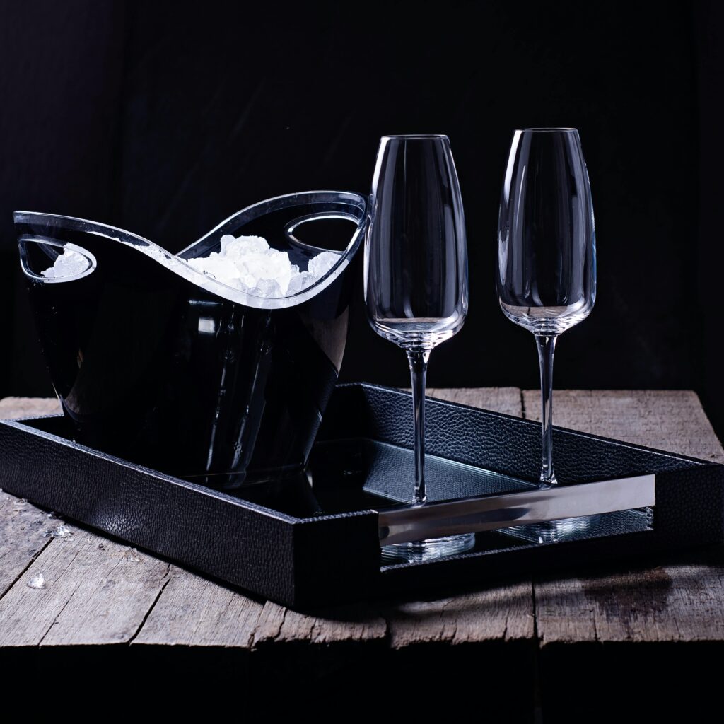 Sophisticated still life featuring an elegant ice bucket and champagne glasses on a rustic table.